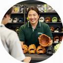野球用品店のスタッフが少年野球用グラブを並べて接客する様子